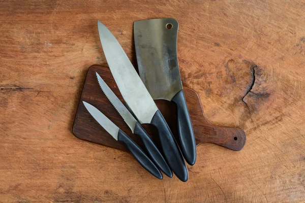 Juego de cuchillos de cocina sobre tabla de cortar de madera sobre tabla de madera vieja —  Fotos de Stock