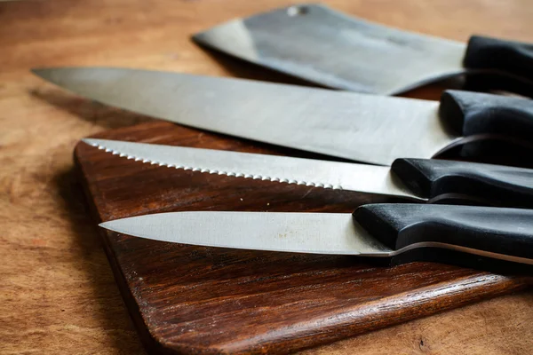 Juego de cuchillos de cocina sobre tabla de cortar de madera sobre tabla de madera vieja — Foto de Stock