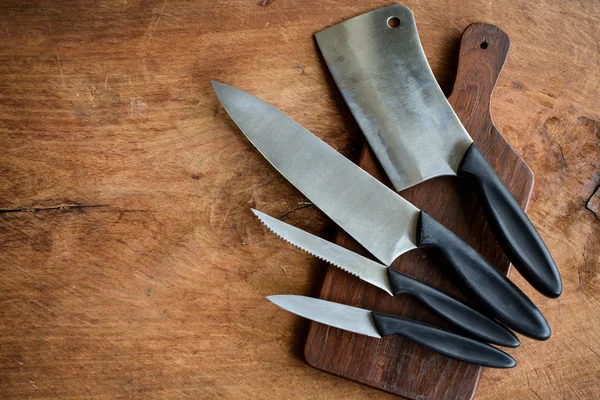 Set of kitchen knifes on wooden cutting board on old wooden tabl — Stock Photo, Image