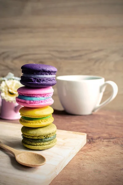 Bunte Makronen und eine Tasse Kaffee auf einem Holztisch — Stockfoto