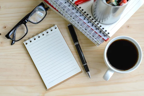 Xícara de café com notebook em branco na mesa de madeira — Fotografia de Stock