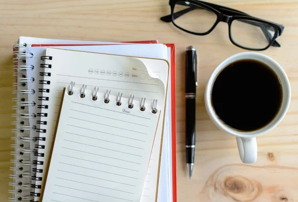 Xícara de café com notebook em branco na mesa de madeira — Fotografia de Stock