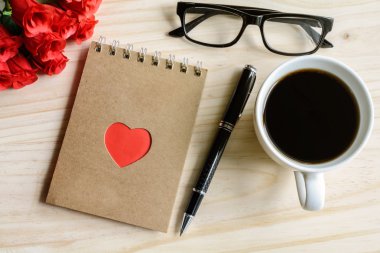 Çiçek ve ahşap masa üstünde not etmek ile kahve