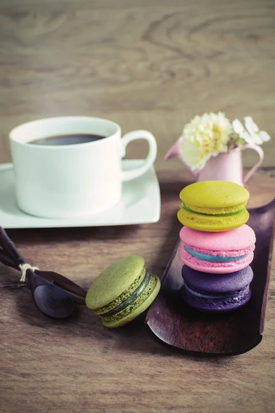 Macaroane colorate și o ceașcă de cafea pe masă de lemn — Fotografie, imagine de stoc