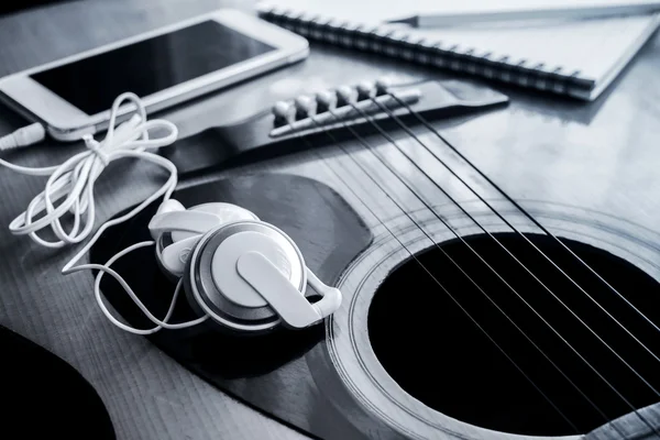 Close-up de fone de ouvido com celular na guitarra — Fotografia de Stock