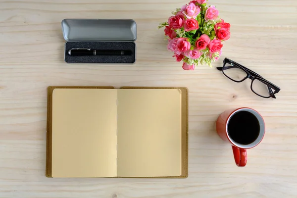 Cup of coffee with notebook and flower on desk — Stock Photo, Image