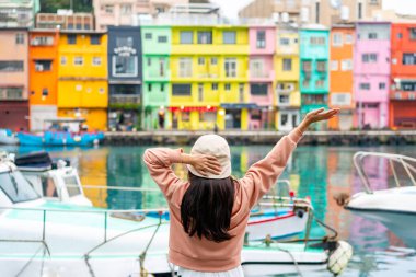 Genç bayan turist, Tayvan 'daki güzel renkli Zhengbin Balık Limanı' nın keyfini çıkarıyor.