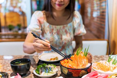 Japon restoranında saşimi yiyen Asyalı genç bir kadın.