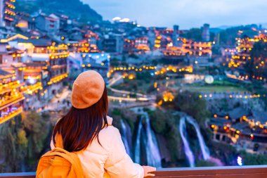 Genç bayan turist, Çin 'in Hunan Eyaleti' nin ünlü turistik beldesi Furong eski kasabasında manzaranın tadını çıkarıyor.