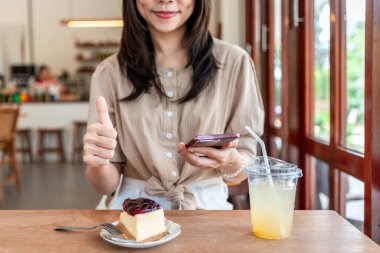 Genç bir kadın sosyal medyada restorandaki yiyecek ve içeceklerin beş yıldızlı memnuniyet derecesini vermek için akıllı telefonu kullanıyor.