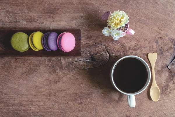 Macaroane colorate și o ceașcă de cafea pe masă de lemn — Fotografie, imagine de stoc