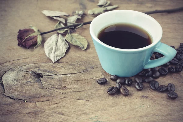 Taza de café con rosa seca sobre una mesa de madera vieja — Foto de Stock