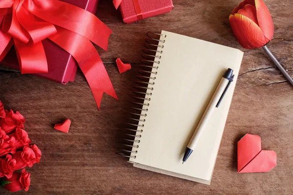 Leeres Notizbuch mit roter Geschenkschachtel und Blume auf Holzgrund — Stockfoto