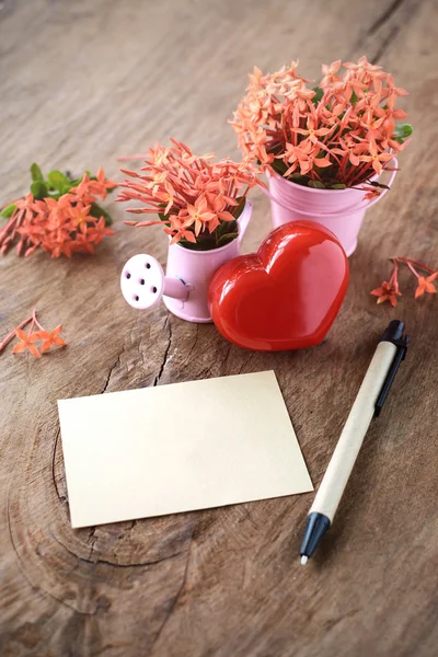 Forma di cuore rosso con fiori e nota su vecchio tavolo di legno — Foto Stock