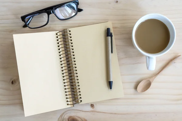 Xícara de café com notebook em branco na mesa de madeira — Fotografia de Stock