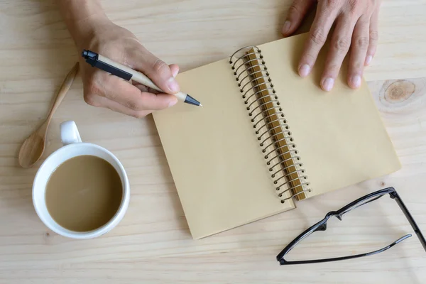 Kopp kaffe med tom anteckningsbok på trä skrivbord — Stockfoto