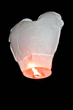 Kalp şeklinde beyaz kağıt Çin feneri gece gökyüzünde uçuşuyor.