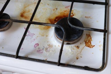 Gıda enkazı ve yağ lekeleriyle dolu kirli gaz ocağı. Yağ lekeli kirli bir gaz ocağı, eski yağ lekeleri, kızarma lekeleri ve yağ lekeleri..