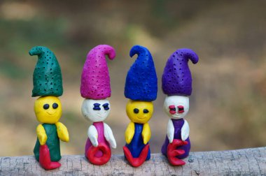 Ormanda dört plastik cüce renkli bir arka planda duruyor. Yanlarında kutsal aşk yazılıdır..