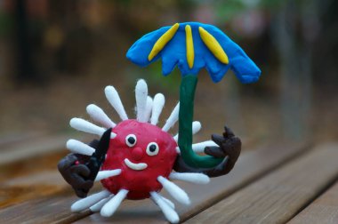 Oyuncak bıçak ve şemsiyeyle plastikten yapılmış virüs heykelciği..