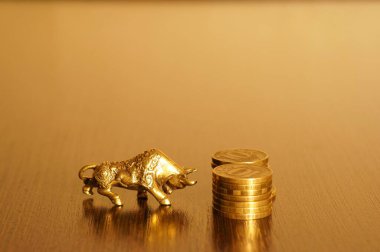 Altın zemin üzerinde bozuk paralar olan metal boğa. Mali sembol.