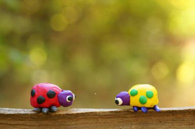Renkli bir arka planda, ormanda plastikten yapılmış iki uğur böceği..