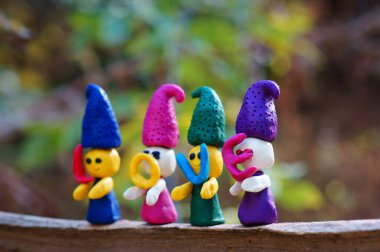 Renkli bir arka planda, ormanda plastikinden yapılmış dört peri masalı cücesinin figürleri. Elflerin ellerinde mektuplar var. Yazıt aşkı..