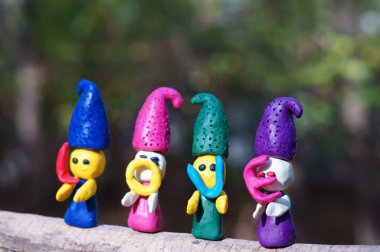 Renkli bir arka planda, ormanda plastikinden yapılmış dört peri masalı cücesinin figürleri. Elflerin ellerinde mektuplar var. Yazıt aşkı..