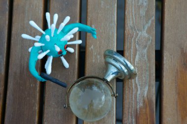 Oyuncak tabancalı bir virüs figürü. Yanında küçük cam bir küre var..