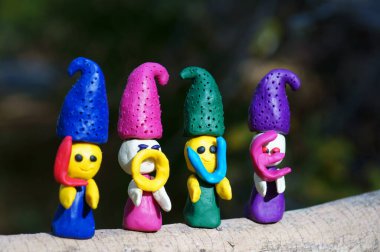 Renkli bir arka planda, ormanda plastikinden yapılmış dört peri masalı cücesinin figürleri. Elflerin ellerinde mektuplar var. Yazıt aşkı..