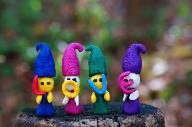 Renkli bir arka planda, ormanda plastikinden yapılmış dört peri masalı cücesinin figürleri. Elflerin ellerinde mektuplar var. Yazıt aşkı..