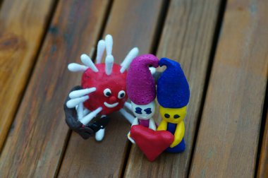 Kil içinden bir kalp tutan iki cüce. Yanında bıçaklı bir virüs figürü var..