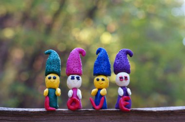 Ormanda dört plastik cüce renkli bir arka planda duruyor. Yanlarında kutsal aşk yazılıdır..