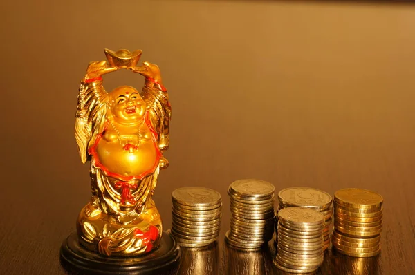 Buddha figure on the table. Next to it is a stack of coins.