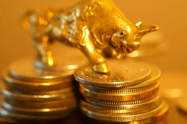 Metal bull with coins on the table. Financial symbol.