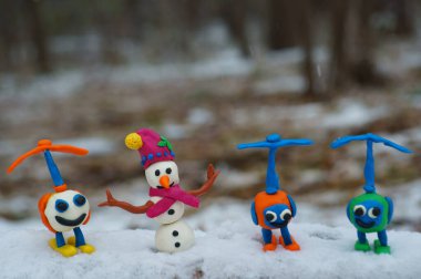 Plastikten yapılmış kırmızı şapkalı bir kardan adam figürü. Oyuncak helikopterlerin yanında..