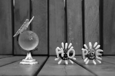 Oyuncak kelebekli küçük camdan bir küre. Virüsün iki figürü ve yazıt umudunun yanında....