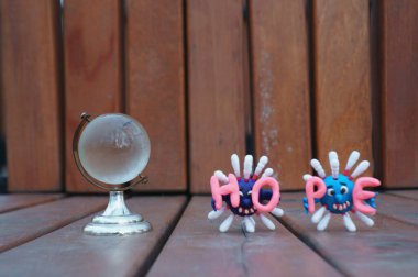 Küçük cam bir küre. Virüsün iki figürü ve yazıt umudunun yanında....