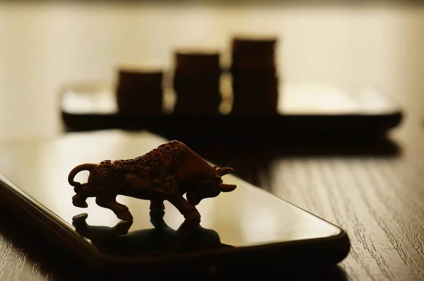 Metal bull and mobile phone on the table.