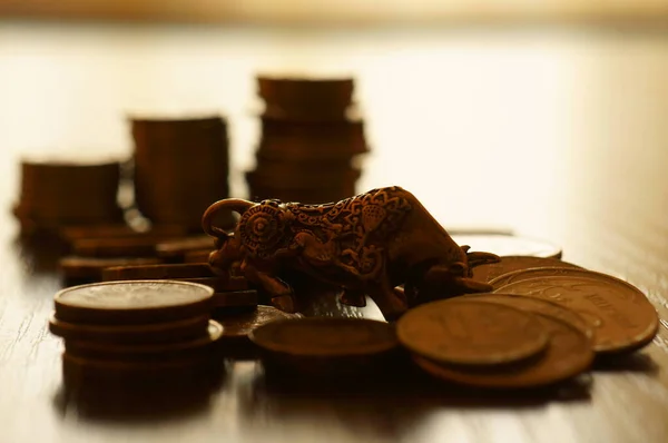 A metal bull and a pile of coins on the table.