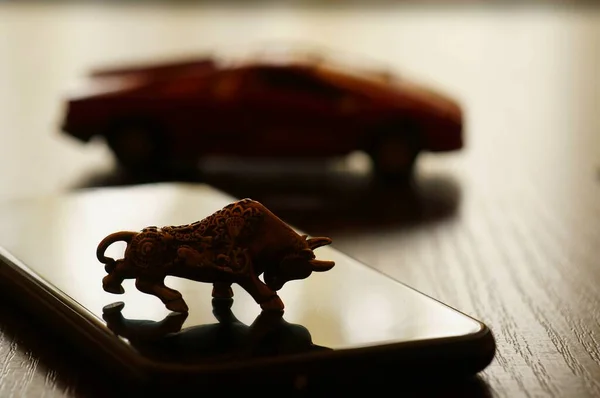 Metal bull on the table. In the background is a toy car.