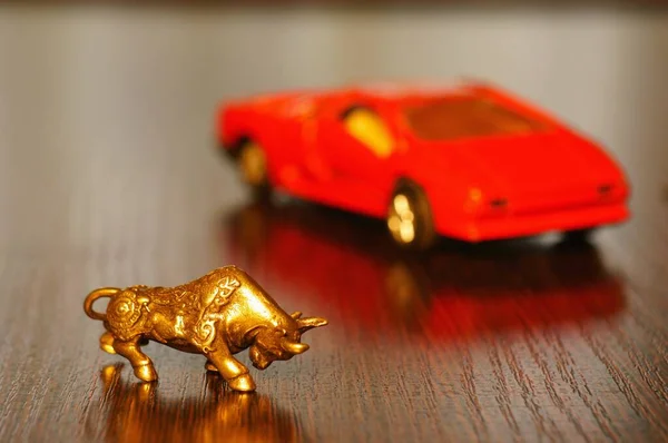 Metal bull on the table. In the background is a toy car.