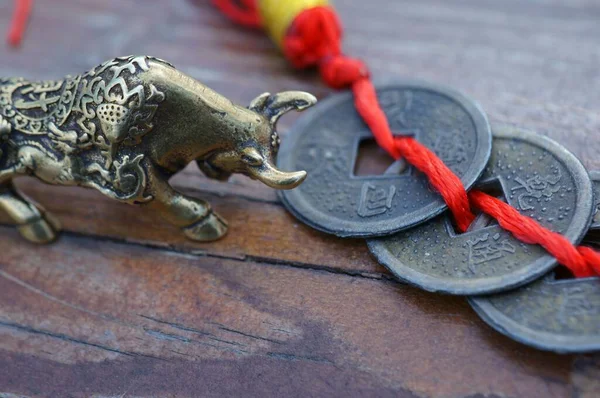 Metal bull figurine close-up. Nearby are Chinese Fengshui coins.