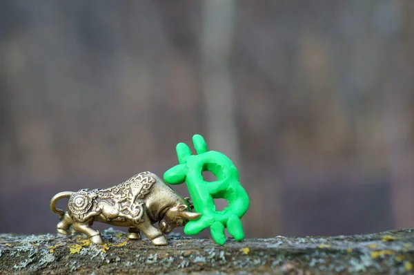Metal bull and Bitcoin sign close-up.