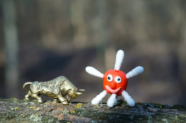 A metal bull and a plasticine virus figurine.