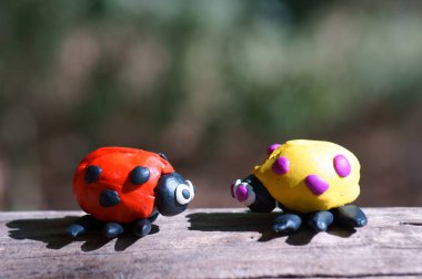Renkli arka planda plastikten yapılmış iki uğur böceği..