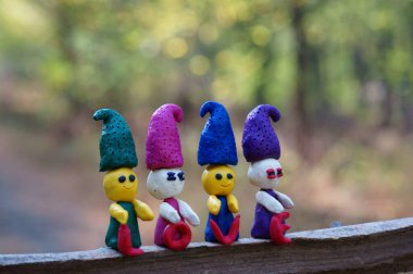 Ormanda dört plastik cüce renkli bir arka planda duruyor. Yanlarında kutsal aşk yazılıdır..