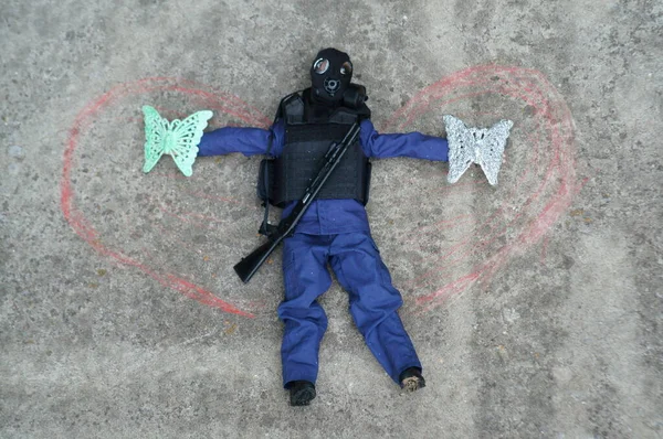 Toy soldier with a gas mask on the concrete surface. On the sides of it are painted wings. Image of an angel. Apocalypse.