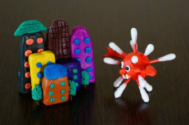 Masanın üzerinde plastikten yapılmış oyuncak ev. Virüsün rakamlarının yanında..