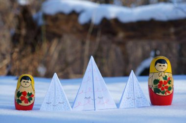 Karlı bir ormanda kağıt oyuncak Noel ağaçları. Matruşka bebeklerinin yanında..